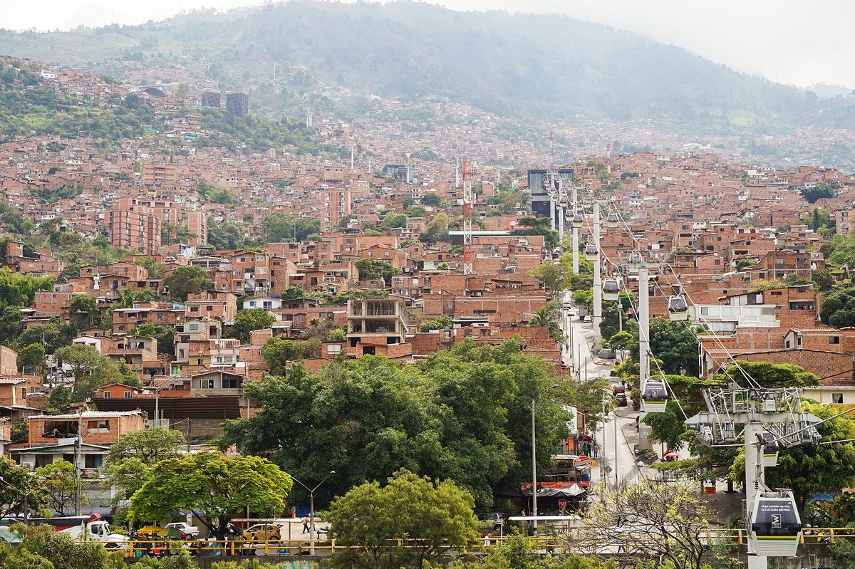 Metrocable cars of Line K gliding above red-brick hillside neighborhoods in Medellín